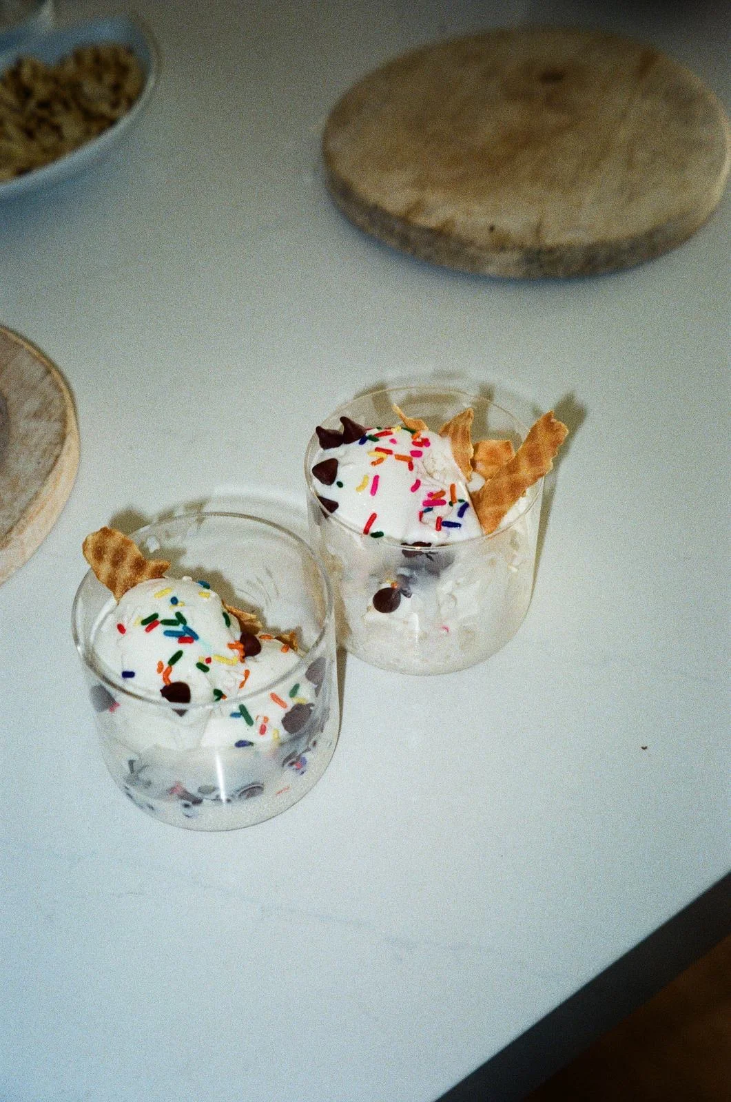 Two glasses of Freezing Point Co liquid nitrogen ice cream topped with sprinkles and waffle pieces