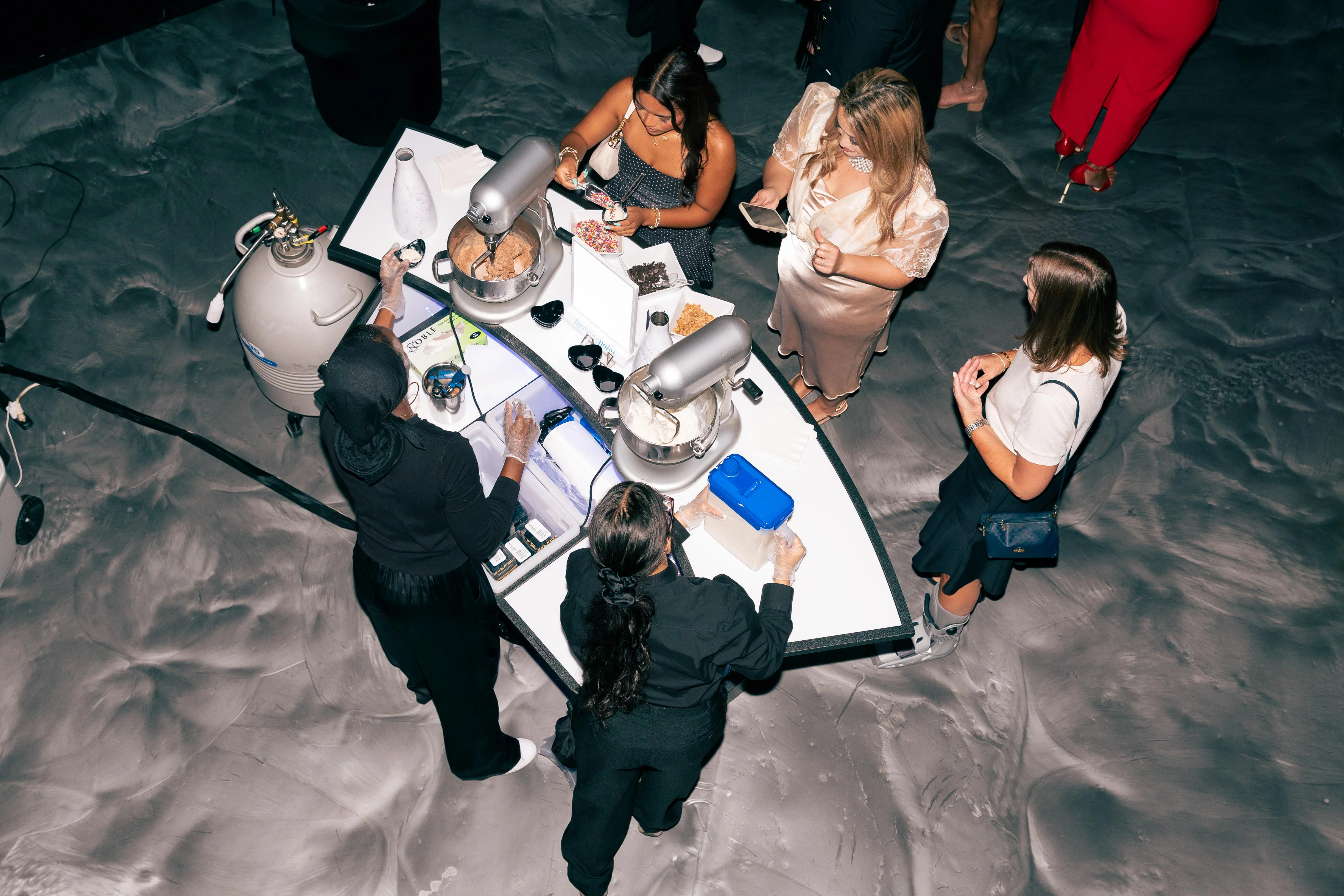 Product launch dessert catering: overhead view of guests gathered at a nitrogen ice cream bar while servers make fresh ice cream