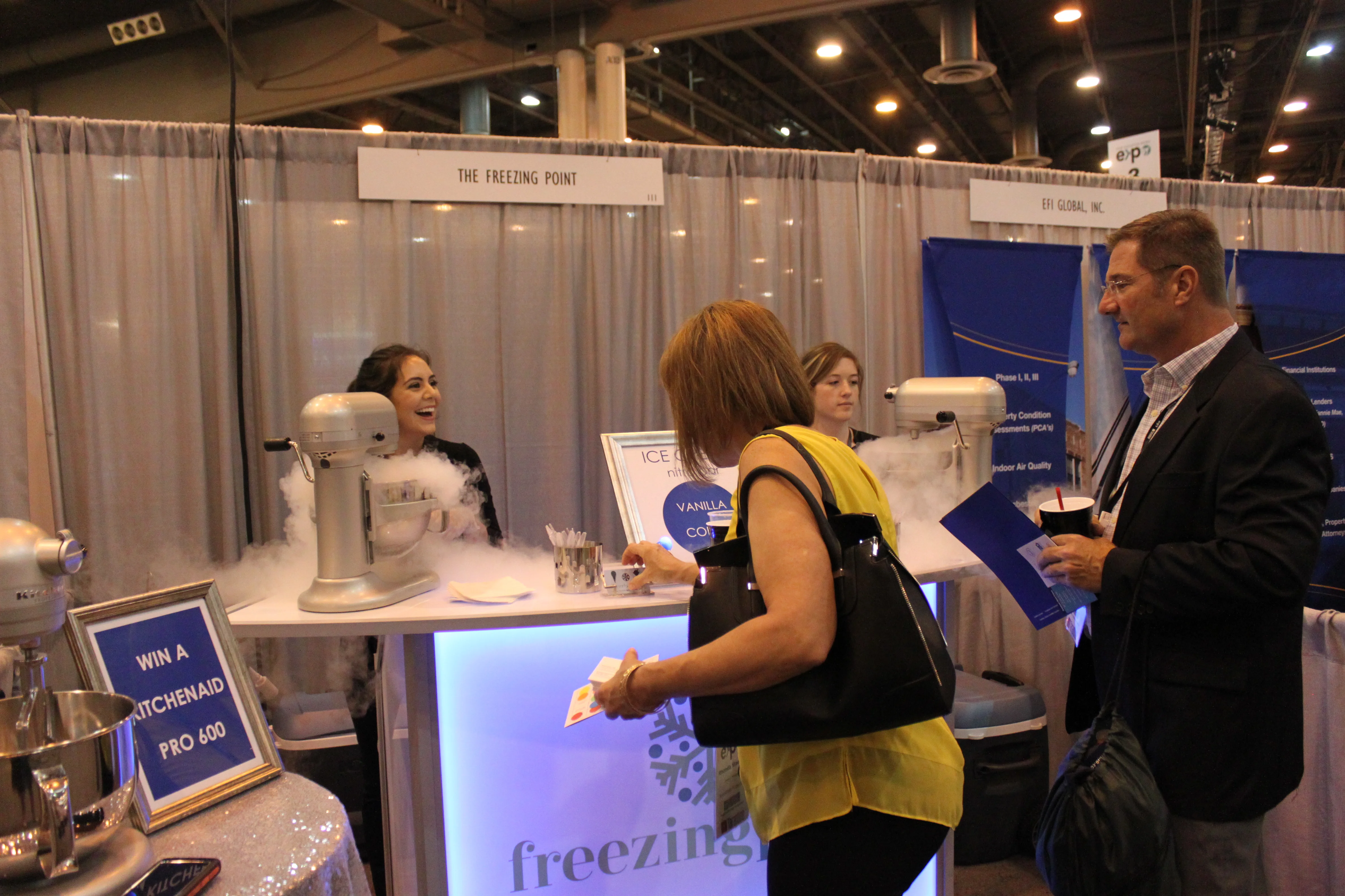 Trade show booth ideas: Freezing Point staff serving nitrogen ice cream to attendees at a lit-up booth at a Houston expo